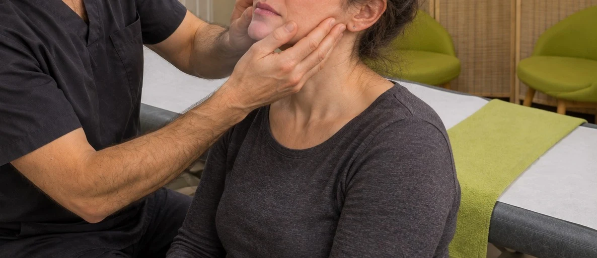 An acupuncturist's hands gently working on a patient's jaw
