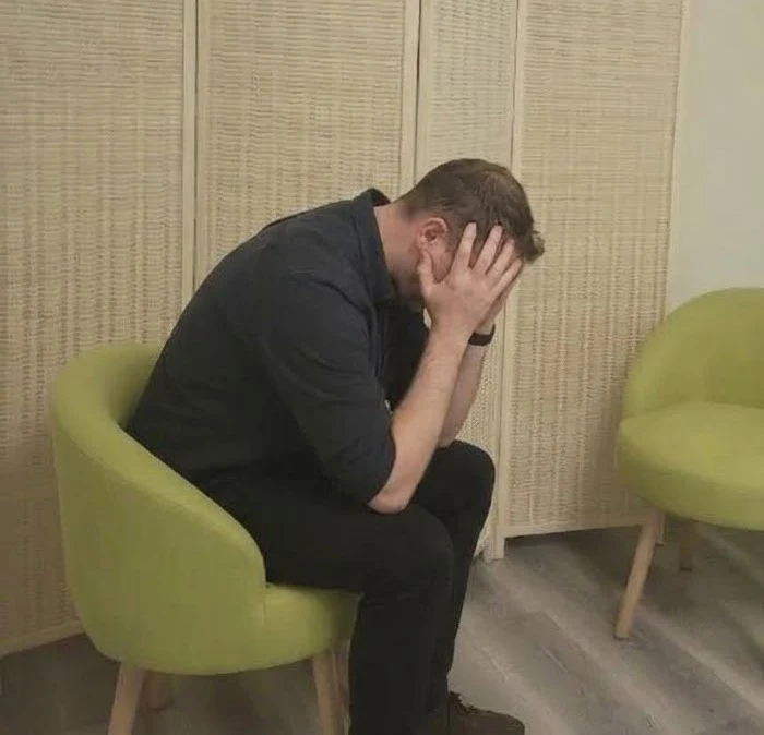 A person sitting with their head in their hands, waiting for treatment