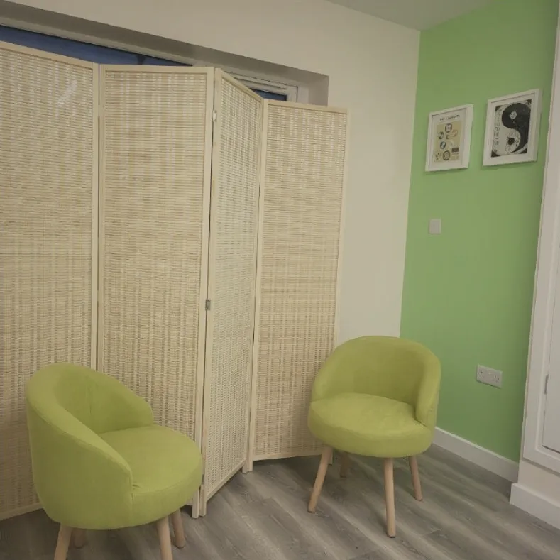 Two green chairs by a bamboo screen